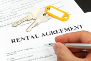 Rental agreement form with signing hand and keys and pen
