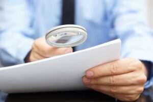 Businessman reviewing contract with magnifying glass