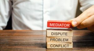 A man holds wooden blocks with the word Mediator, dispute, problem, conflict. 