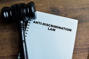 Anti-Discrimination Law write on book with gavel isolated on Wooden Table.