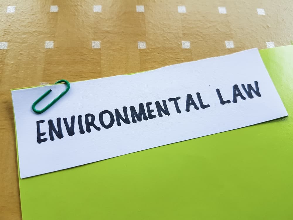 Environmental law written on a white paper on table background.